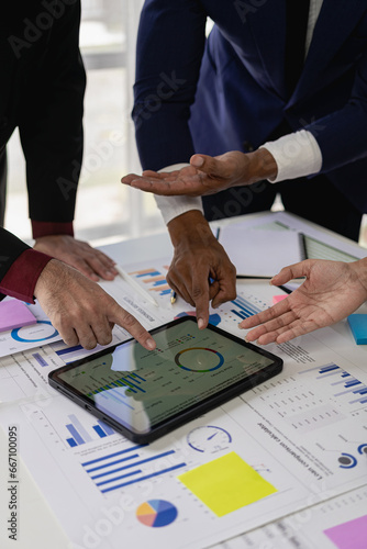 Business team of 3 colleagues discussing new financial graph data on the table An accountant is analyzing data charts, graphs, and dashboards on a laptop screen. vertical picture