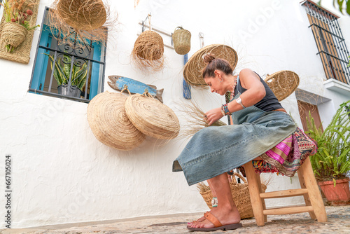 Photos Side view of Hispanic woman weaving a basket with esparto fibers