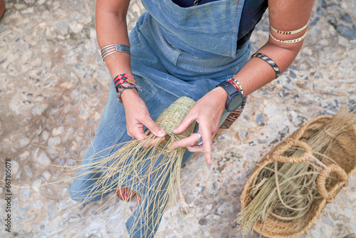 Abobe view of Hispanic woman weaving a basket with esparto fibers. Manual work, tradition and culture. Close up. photo