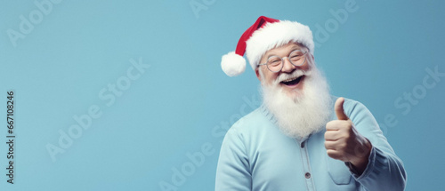 Portrait of santa claus showing a thumb up on light blue background photo