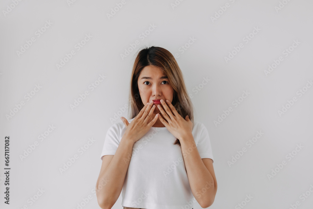 Asian Thai woman surprised and unbelievable doubt face, distrustful looking at camera and covering mouth by two hands, dishonest isolated on white background wall. Asian Thai woman surprised and unbelievable doubt face, distrustful looking at camera and covering mouth by two hands, dishonest isolated on white background wall.