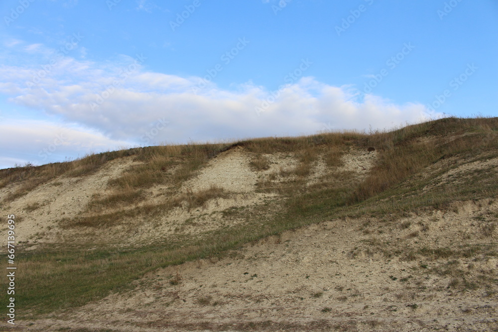 A grassy hill with a hill in the background A grassy hill with a hill in the background