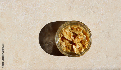 Walnuts soaked in water in a glass bowl on a light beige background.