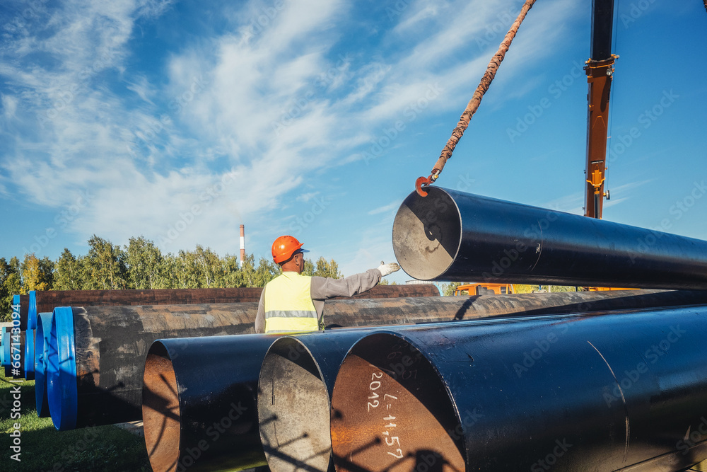 Obraz Slinger unloads large gasification pipes on summer day. Pipes for ...