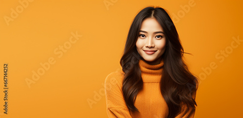 studio portrait of happy asian woman in orange sweater on orange background, advertising,promotion,halloween,thanksgiving,autumn etc