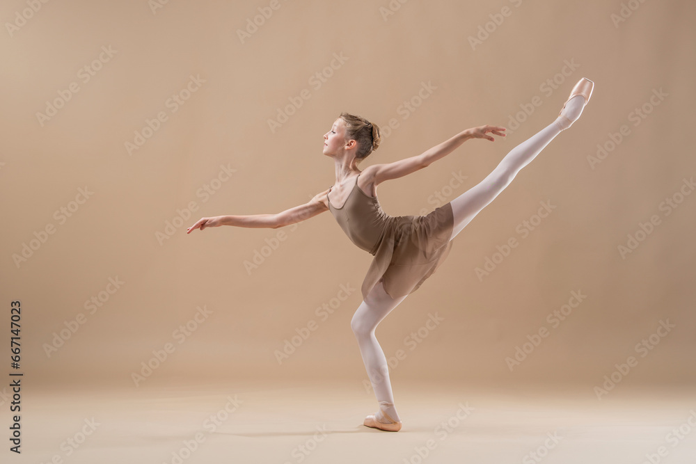 Obraz premium Beautiful young girl professional student ballerina in pointe shoes and a leotard on a light beige background.
