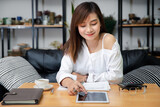Young Business woman hold pen and pointing on digital tablet for analysis and budget financial accounting with growth statistics chart and graph on desk. Business, education, freelance concept.