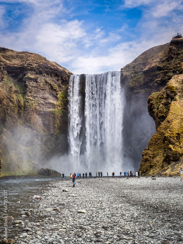 Visitors at the foot of Skogafoss, a prominent waterfall in South Iceland.