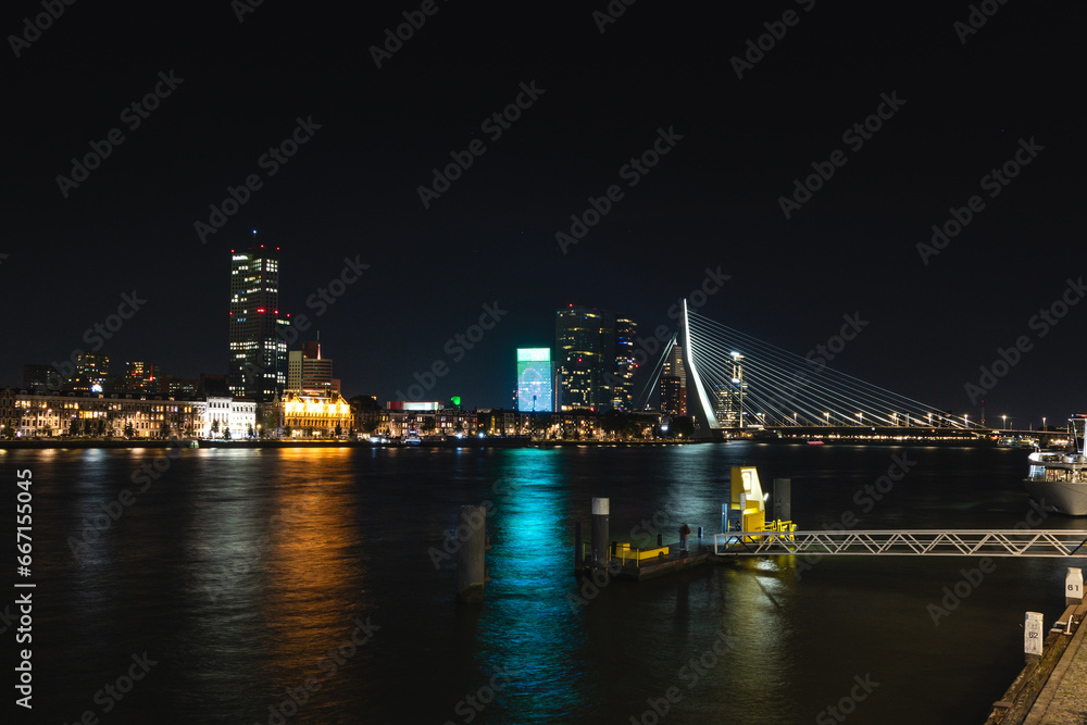 View of the canal and the opposite illuminated bank with lots of illuminated skyscrapers during late night in Rotterdam, Netherlands