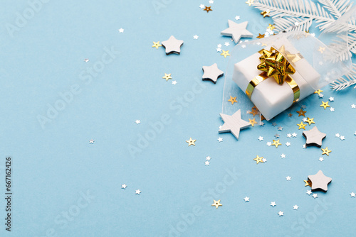 Christmas gift box with decorations and sparkles on blue bacground.