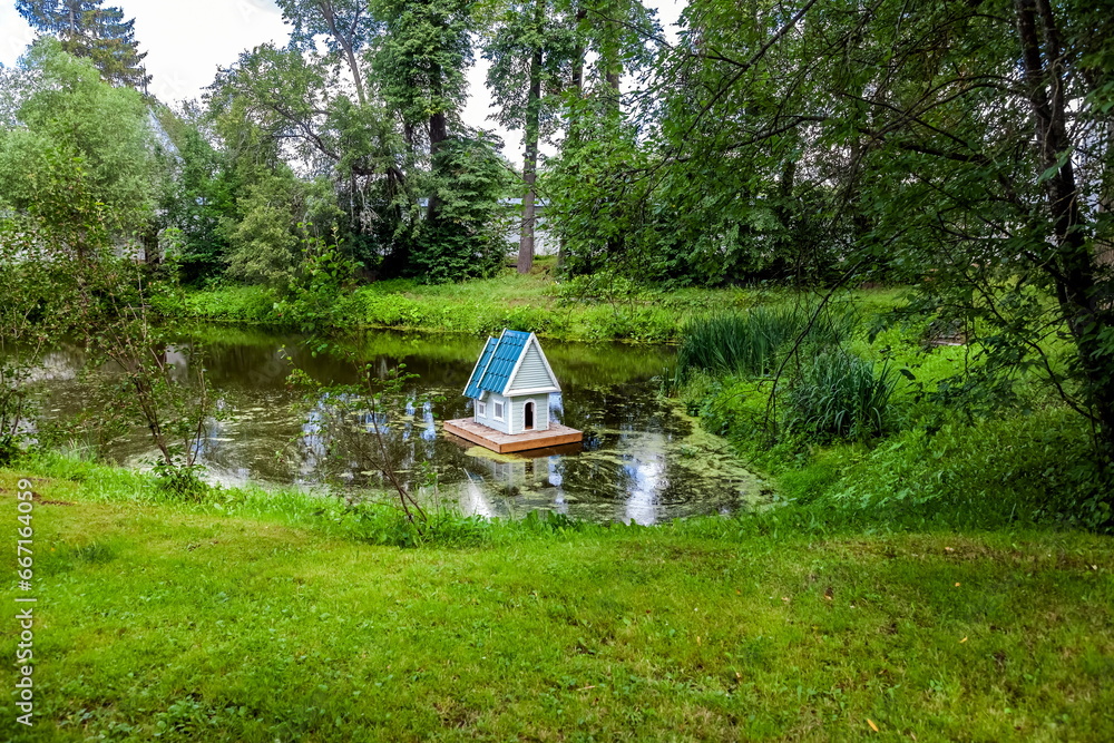 Wooden house for swans on a small artificial lake in summer