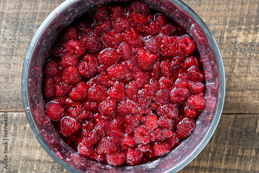 Fresh red raspberry berry, covered with granulated sugar for jam preparation in bowl, top view, closeup. Background and texture of raspberries with sugar Fresh red raspberry berry, covered with granulated sugar for jam preparation in bowl, top view, closeup. Background and texture of raspberries with sugar