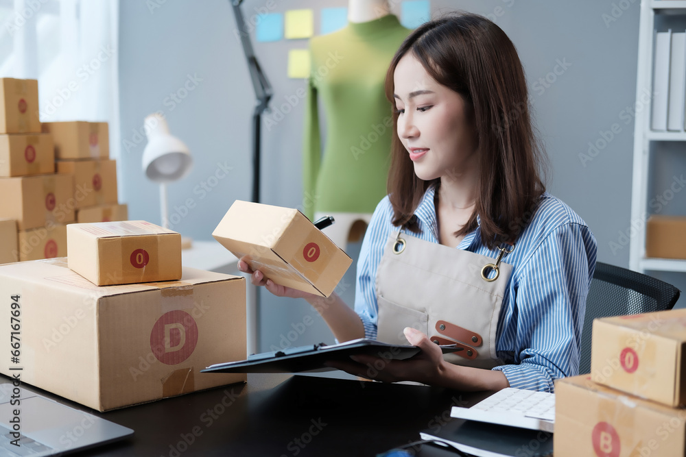 Startup SME small business entrepreneur SME or freelance Asian woman using a laptop with box, online marketing packaging box and delivery, SME concept. Startup SME small business entrepreneur SME or freelance Asian woman using a laptop with box, online marketing packaging box and delivery, SME concept.