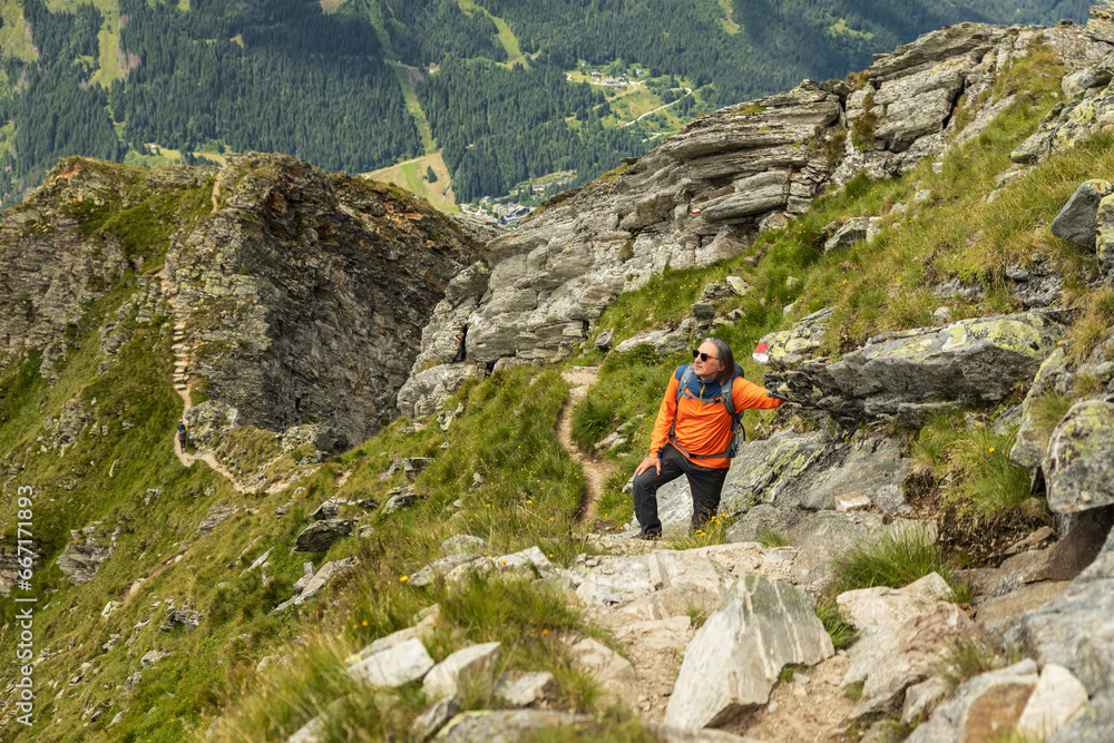 Man stopped on climb on rocky trail and resting on rocky ridge background, Austria