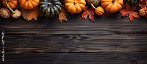 Autumn themed scene with pumpkins and leaves on a wooden background viewed from above