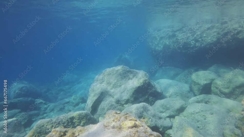 Underwater seascape with stones reef under water reflected on surface. Shallow water landscape with big stones in sun glare and surface on shallow water Underwater seascape with stones reef under water reflected on surface. Shallow water landscape with big stones in sun glare and surface on shallow water
