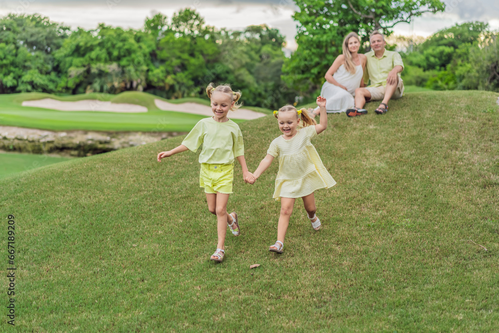 Fototapeta premium A happy family, two girls, dad, and a pregnant mom, enjoys quality time together on a lush green lawn, creating cherished memories of togetherness