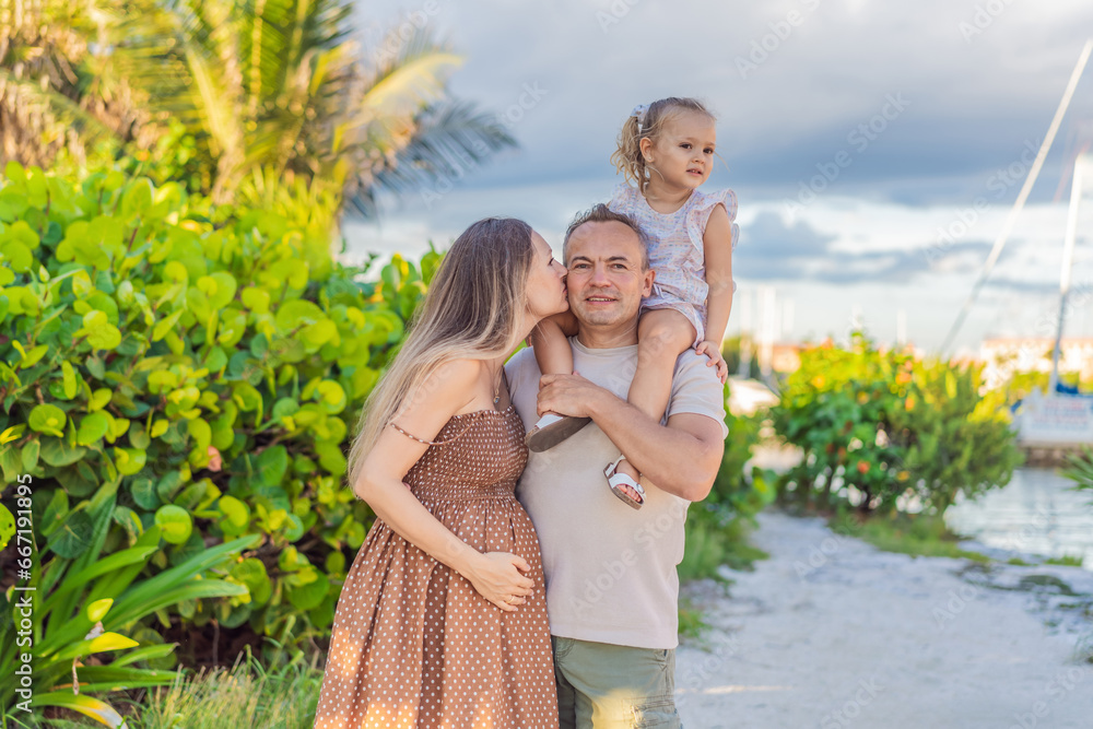 A happy, mature couple over 40 with their two daughters, enjoying a leisurely walk in a park, their joy evident as they embrace the journey of pregnancy later in life