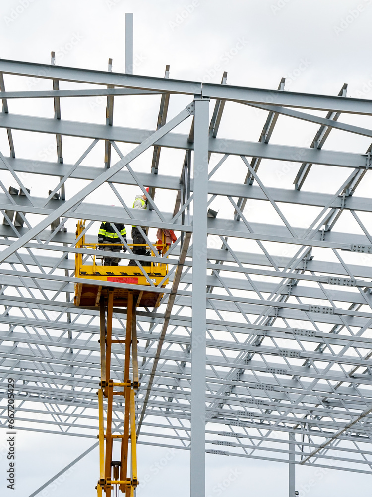 Fototapeta premium Complex large volume steel frame structure assembly using self propelled scissor lift platform