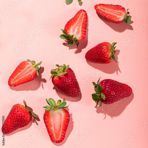 Fototapeta Naklejka Na Ścianę i Meble -  Fresh strawberries cut into slices on a pink background. Square crop, sunshine and shadows