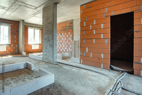 The interior of the apartment without finishing. A room in a new building without repair, brick walls. Repair work on the construction site of a residential apartment. 