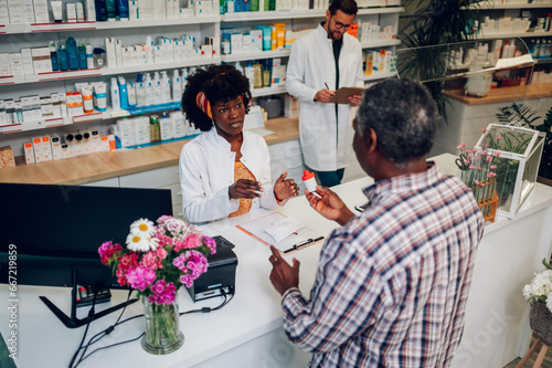 African american woman pharmacist selling drugs to a senior customer in a pharmacy