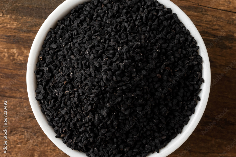 Black cumin seeds in bowl on rustic wooden table. Top view Black cumin seeds in bowl on rustic wooden table. Top view