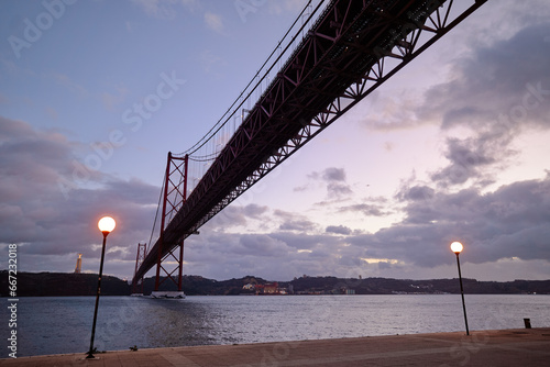 Beautiful landscape with suspension 25 April bridge bridge over the Tagus river in Lisbon at night time, Portugal.