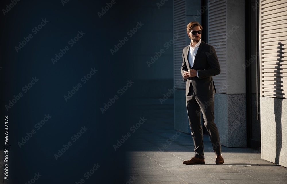 Fototapeta premium Elegant handsome man in classic suit standing near the office building.
