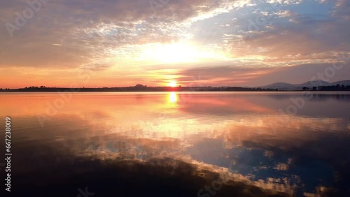 Flying through a dead tree over a lake during a golden sunrise. photo