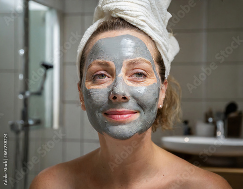 A woman applying a clay mask on her face