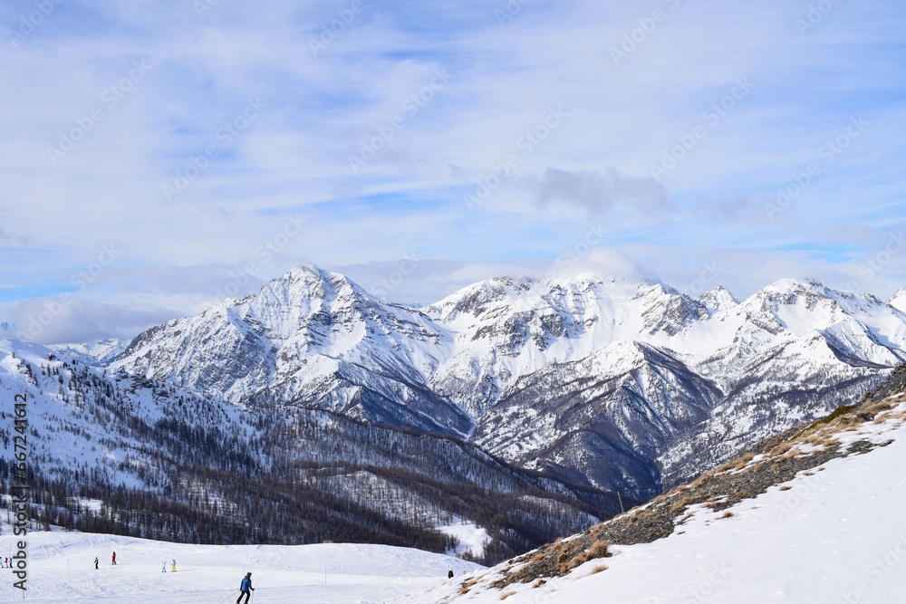 Stunning view of snowy Italian mountain range and valley from ski slope in Sauze D'Oulx ski resort, Turin, Italy. Beautiful Italian alpine peaks of snow capped mountains in the Piedmont region.
