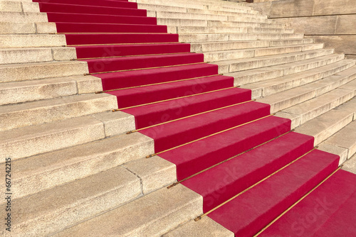 A vibrant red carpet elegantly adorns the steps of a historic house or theater, providing an inviting path for visitors during special events.