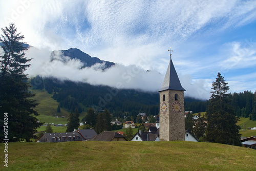 Obraz na płótnie Beautiful swiss alpine countryside with a medieval bell tower with a clock and Rothorn mountain on background in Churwalden village in Switzerland formerly Parpan w salonie