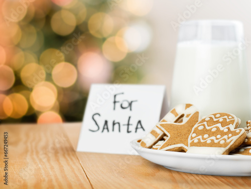 gingerbread cookies and milk for Santa Claus on a wooden table against the background of defocus lights