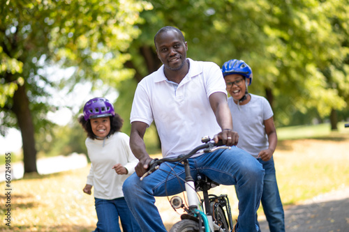 Happy family riding a bike in a park and having fun together