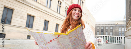 Redhead girl, tourist explores city, looks at paper map to find way for historical landmarks, woman on her trip around euope searches for sightseeing photo