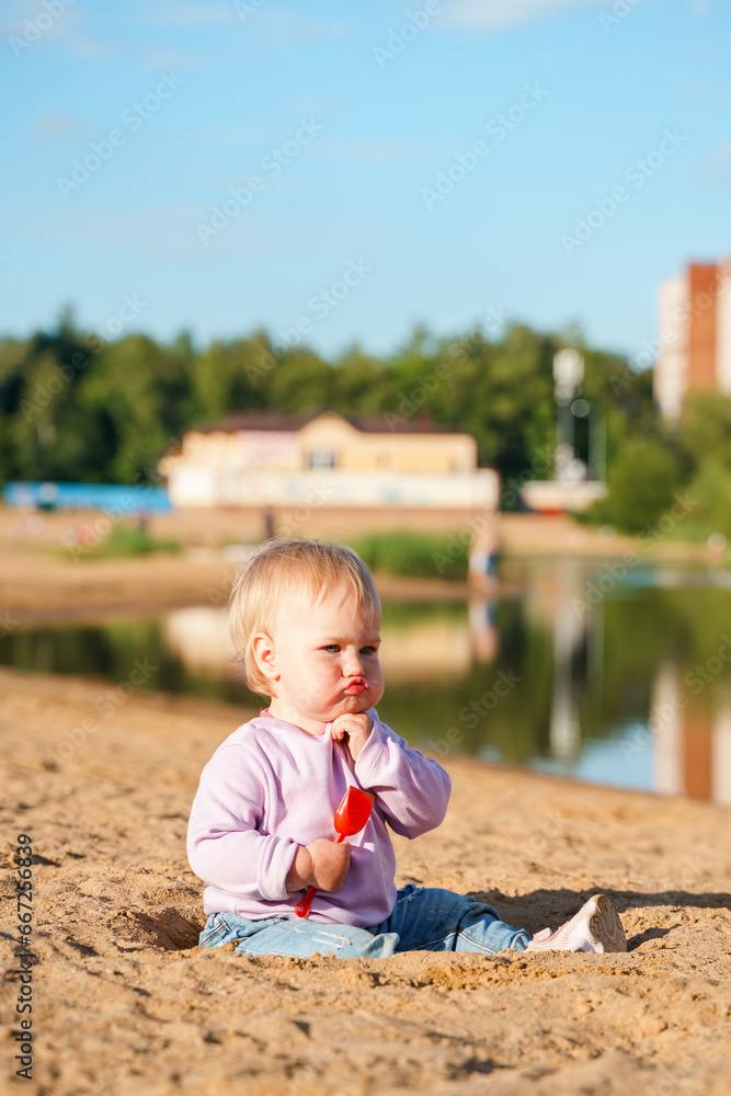 Cute little kid baby in jeans on the shore of the lake in the evening Cute little kid baby in jeans on the shore of the lake in the evening