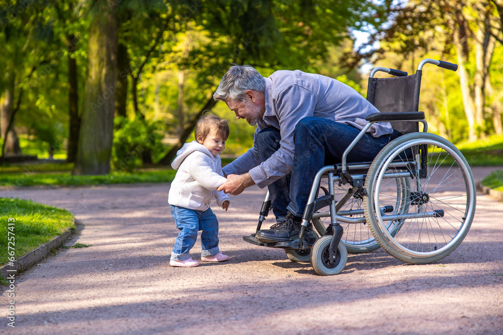 Dad on wheelchair playing with his little son in the park
