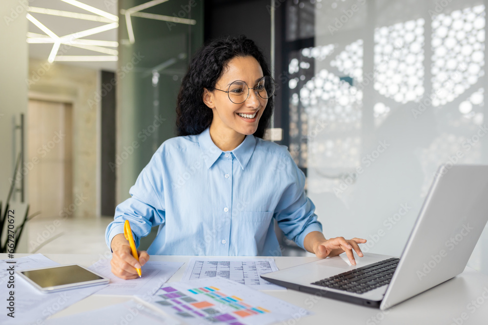 Φωτογραφία Young successful Indian woman paperwork, businesswoman records data, fills tables and checks invoices, reports and contracts