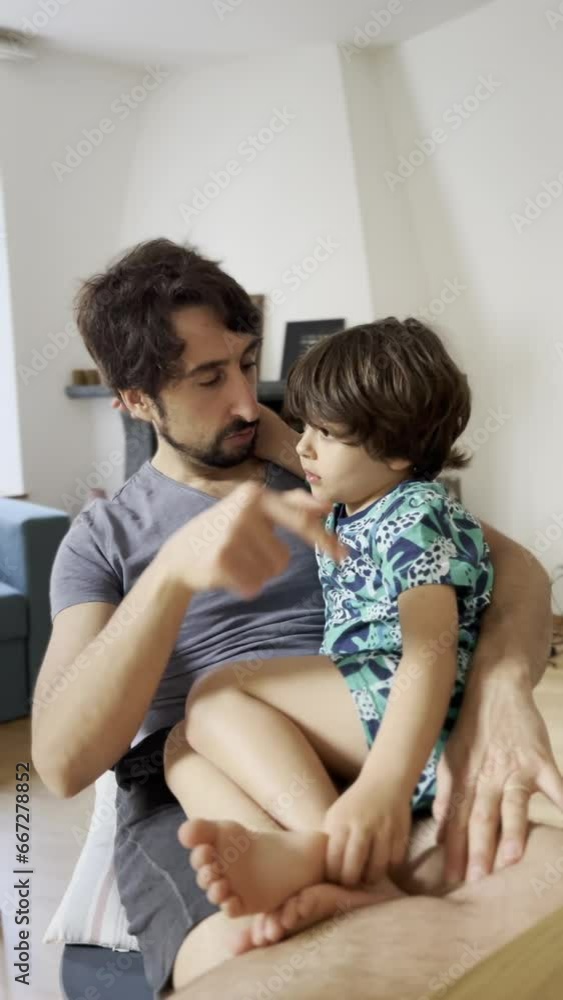 Teaching and Bonding Moment - Father Imparts Knowledge to His Son, Who Sits in His Lap, Listening Attentively Teaching and Bonding Moment - Father Imparts Knowledge to His Son, Who Sits in His Lap, Listening Attentively