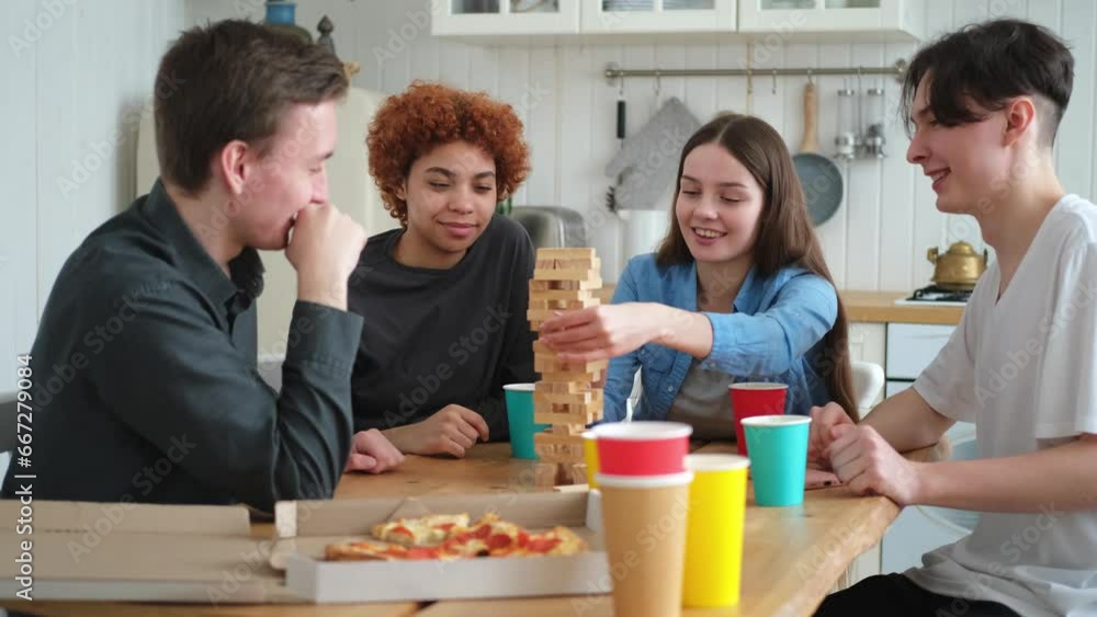 Home party. Friends spending time together playing in board game crash wooden tower at home. Happy diverse group having fun together indoor. Mixed race young buddies best friends enjoying weekend