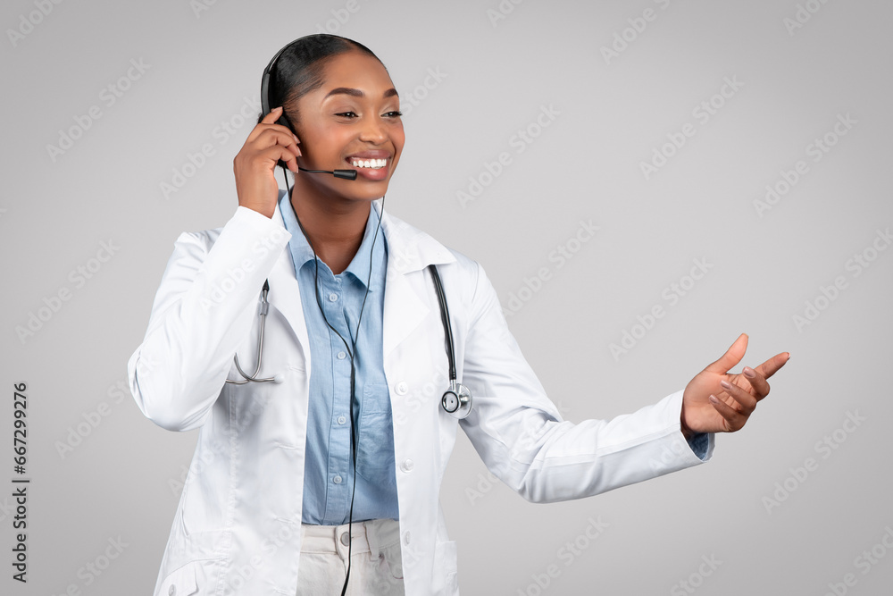 Cheerful mature black woman doctor in white coat gestures to copy space Cheerful mature black woman doctor in white coat gestures to copy space
