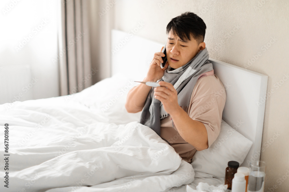 Sick Mature Asian Man Holding Thermometer And Calling Doctor Sick Mature Asian Man Holding Thermometer And Calling Doctor