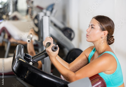 Young athletic woman training her arm muscles using machine in gym © JackF