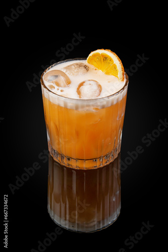 Alcoholic cocktail based on tequila, aperol, passion fruit puree and grapefruit juice and egg white. Drink in a glass on dark background with reflection
