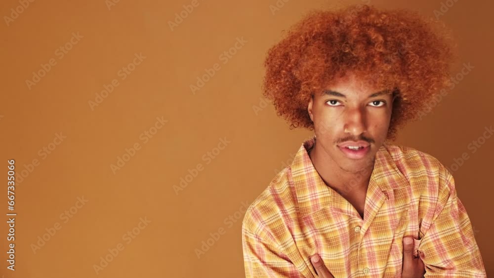 Guy crosses his arms and looks at the camera isolated on brown background in studio Guy crosses his arms and looks at the camera isolated on brown background in studio
