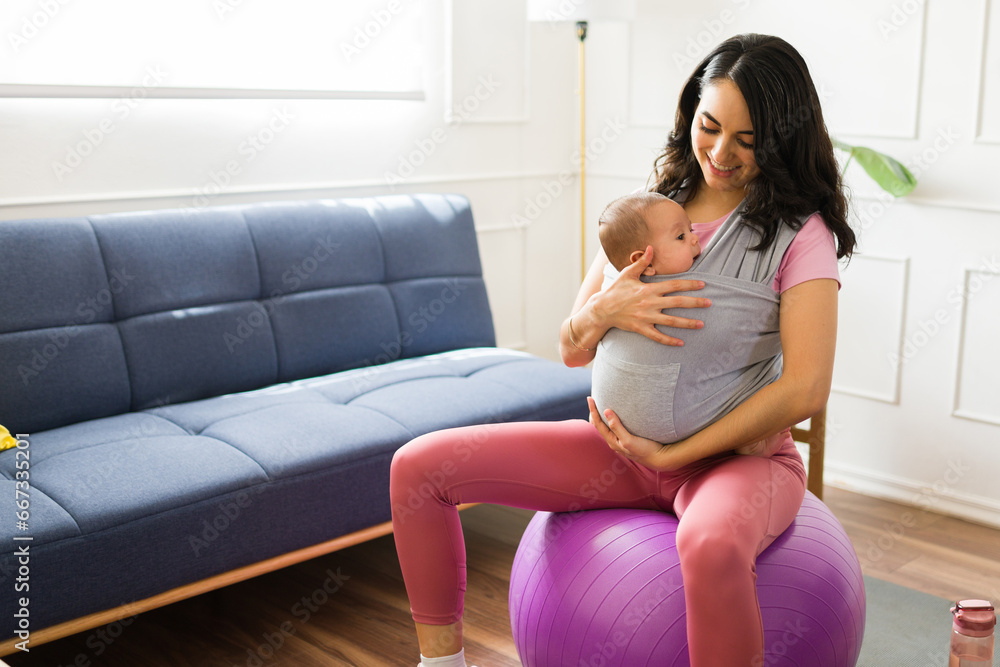 Fit active mom doing pilates with a baby carrier Fit active mom doing pilates with a baby carrier