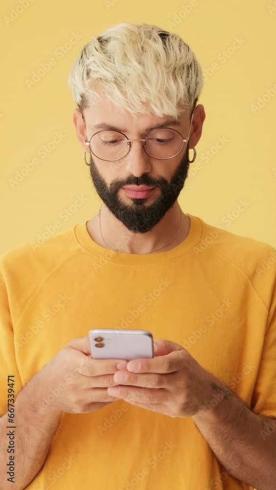 Man with phone in his hands with mockup space isolated on yellow background in studio Man with phone in his hands with mockup space isolated on yellow background in studio