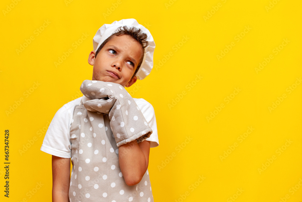 pensive little boy african american baker in uniform and gloves thinks and plans on yellow isolated background pensive little boy african american baker in uniform and gloves thinks and plans on yellow isolated background